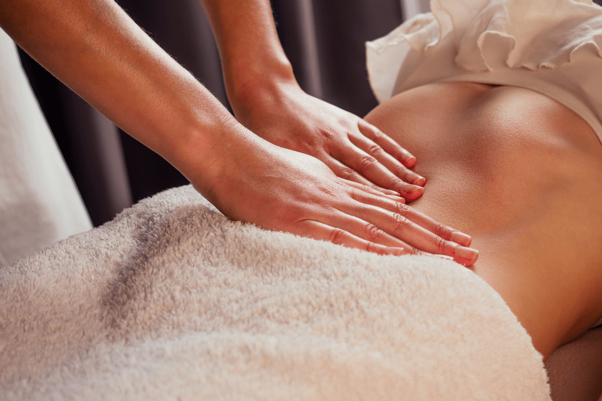 Toque respeitoso e suave na base da coluna, ilustrando a abordagem terapêutica e não-invasiva da massagem Yoni e Lingam.