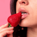 Close sensual de mulher mordendo um morango, ilustrando estratégias profissionais sobre como posso ganhar dinheiro com conteúdo adulto.