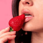 Close sensual de mulher mordendo um morango, ilustrando estratégias profissionais sobre como posso ganhar dinheiro com conteúdo adulto.