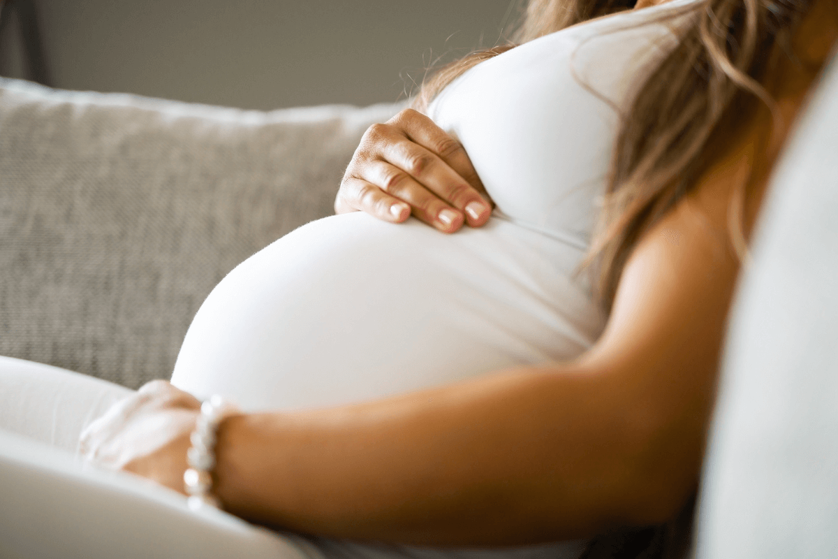 Mulher grávida segurando a barriga com as mãos de forma protetora, ilustrando uma das principais contraindicações absolutas sobre se é bom usar massageador na barriga durante a gestação.
