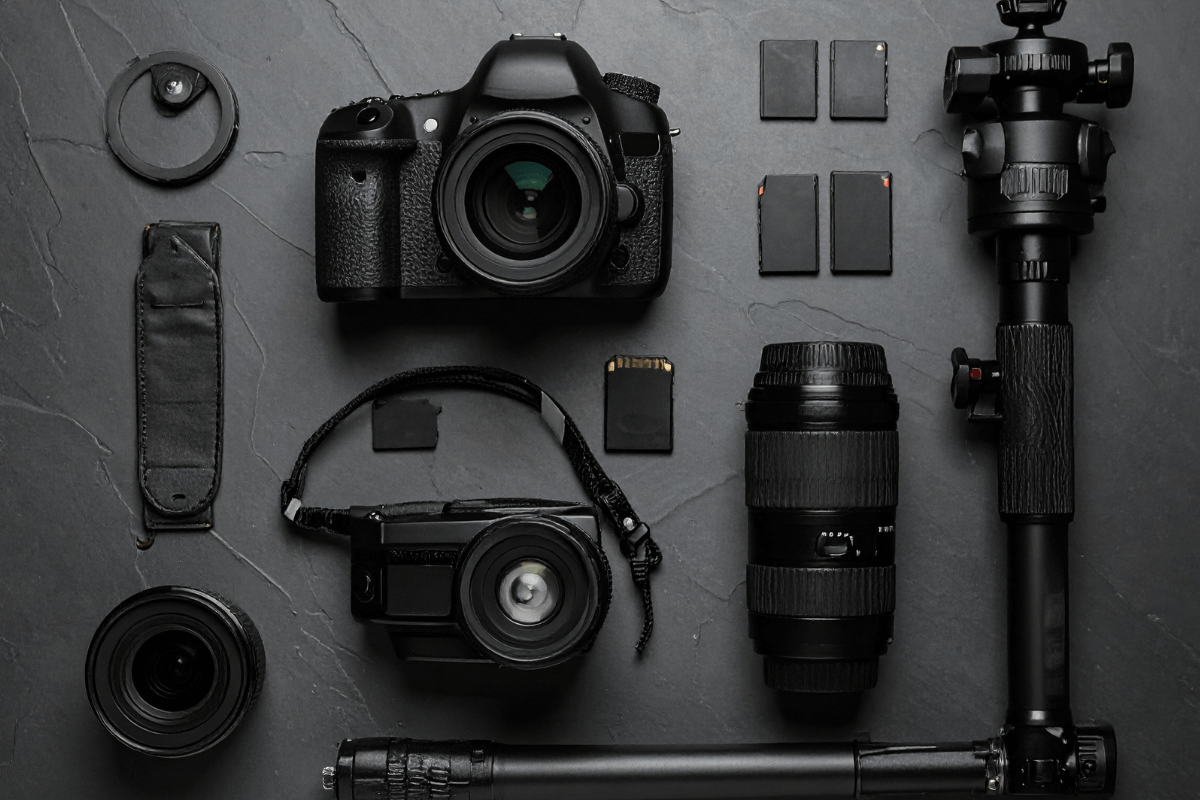 Conjunto de equipamentos de fotografia profissional com câmera, lentes, tripé e acessórios organizados em fundo escuro, para produção de conteúdo adulto de alta qualidade.