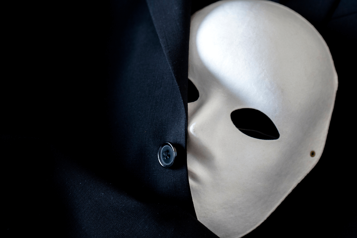 Máscara branca parcialmente coberta por tecido preto, simbolizando o anonimato de quem lucra como afiliado ou curador de conteúdo adulto sem precisar produzir material próprio.