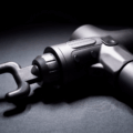 Close-up da pistola massageadora muscular profissional na cor preta com a ponteira garfo acoplada, ideal para relaxamento da coluna e alívio de tensão.