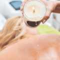 Mulher recebendo massagem com velas (Candle Massage), um dos tipos de massagens corporais relaxantes mais procurados em clínicas de estética.
