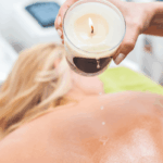 Mulher recebendo massagem com velas (Candle Massage), um dos tipos de massagens corporais relaxantes mais procurados em clínicas de estética.