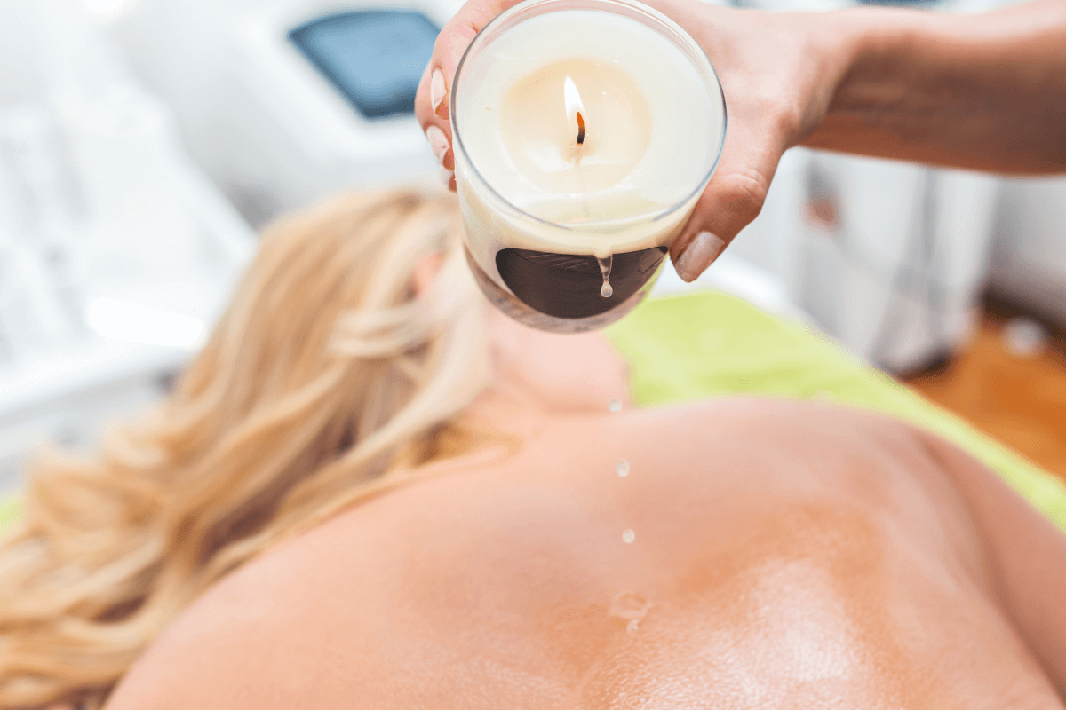 Mulher recebendo massagem com velas (Candle Massage), um dos tipos de massagens corporais relaxantes mais procurados em clínicas de estética.