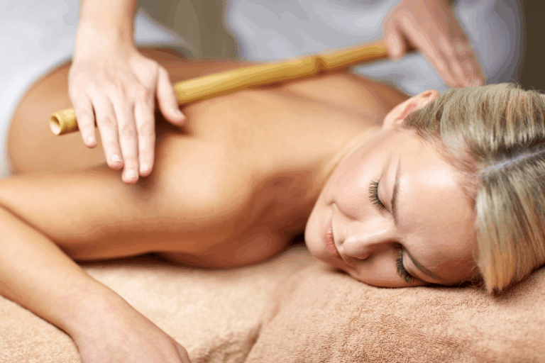 Mulher deitada recebendo massagem com hastes de bambu nas costas em clínica de estética, ilustrando o artigo sobre qual o valor de uma sessão de bambuterapia.