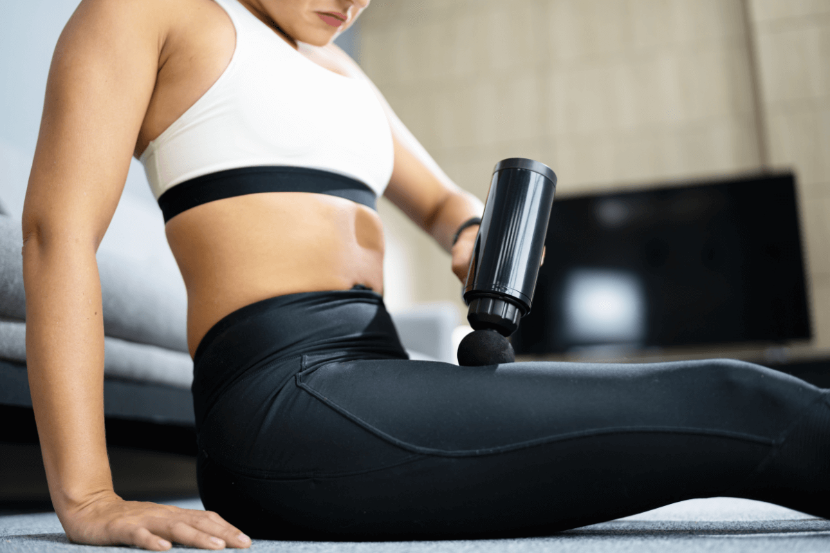 Mulher observando atentamente a região da coxa durante a aplicação da pistola massageadora, monitorando possíveis sinais de que passou do tempo, como vermelhidão ou irritação na pele.